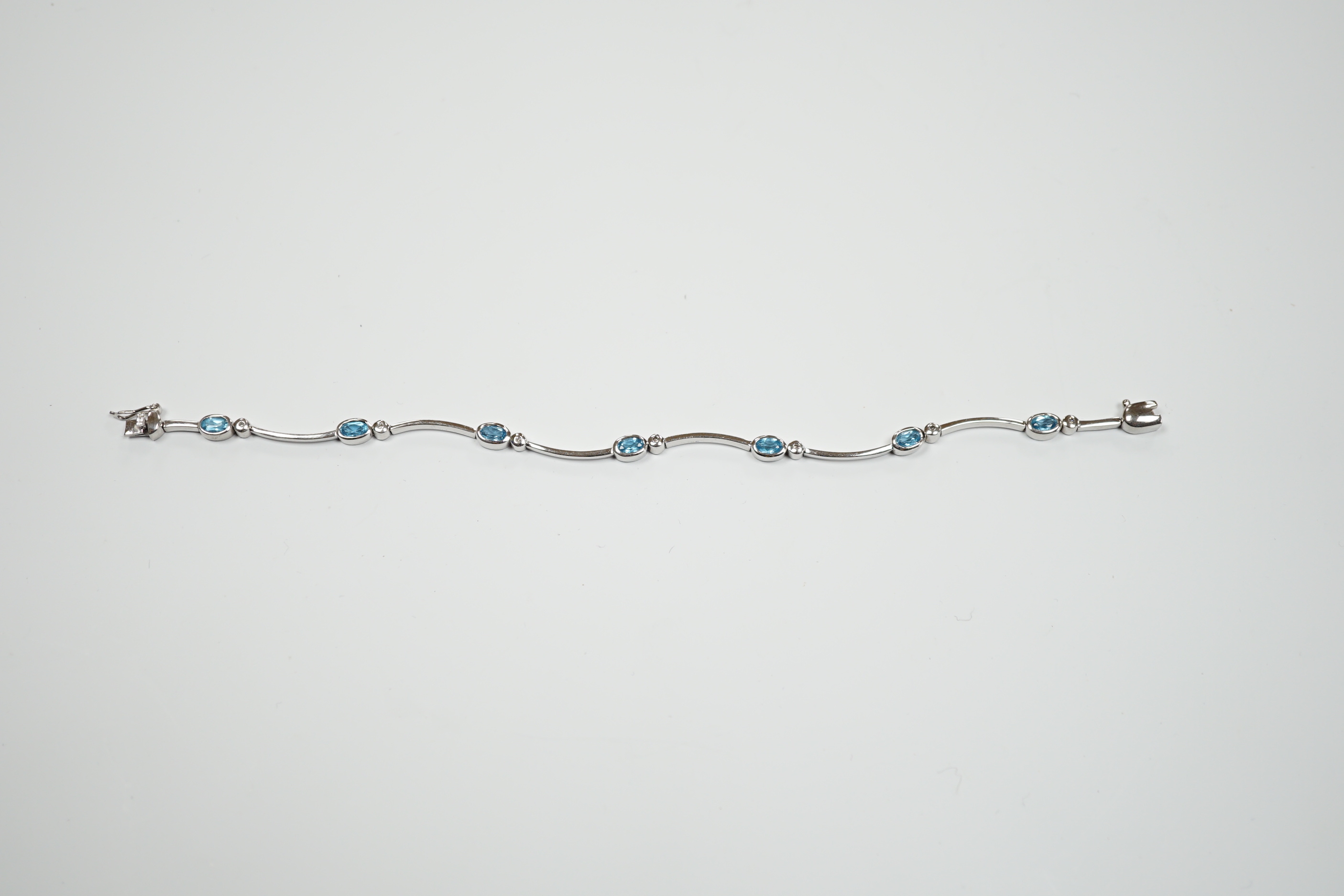 A modern 9ct white gold blue topaz and diamond chip set bracelet, 18.5cm, gross weight 9.1 grams.